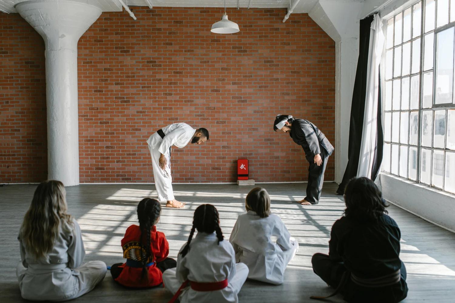 Kinder in der Karate-Klasse und ein Trainer verneigen sich voreinander